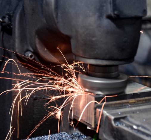 Primer plano de una operación de rectificado o amolado sobre una pieza metálica.
Se ve el disco de la máquina en contacto con el metal, generando chispas.
Imagen de un proceso de mecanizado en un entorno industrial.
